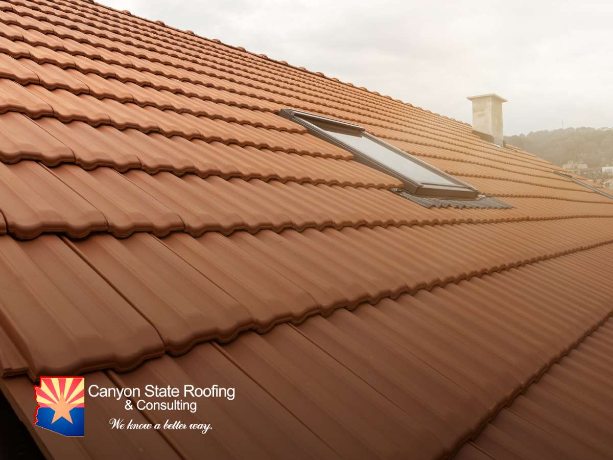 Close-up view of terracotta roof tiles on a residential house, with a chimney in the background and a skylight integrated into the roofing